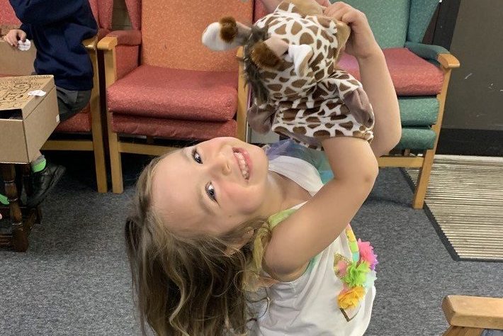 Ukranian refugee girl playing with giraffe puppet